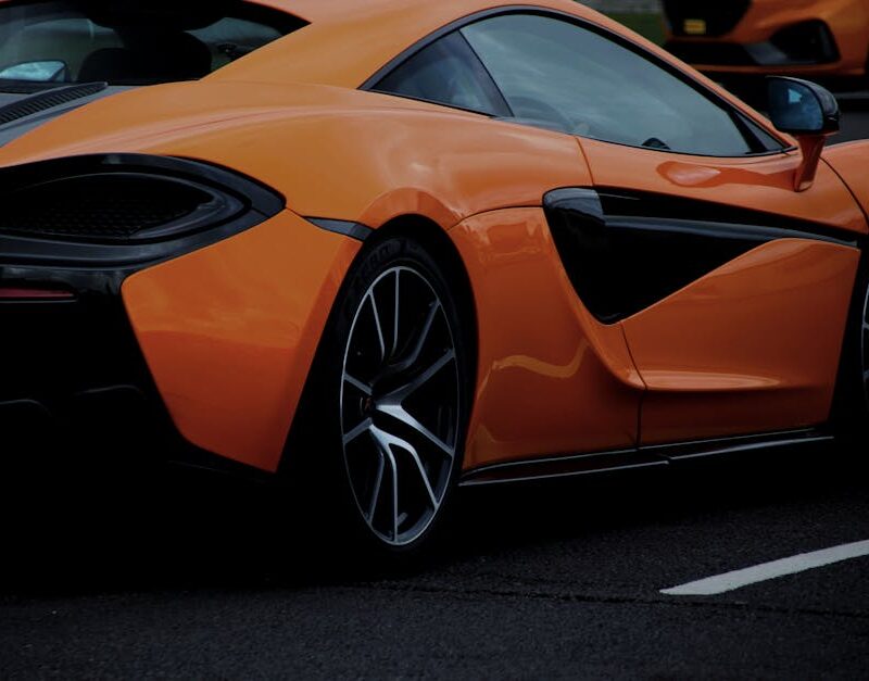 Luxury Cars - A dynamic shot of an orange sports car on a road #15713937